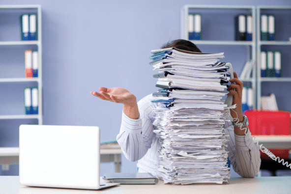 Admin Overload - person with pile of paperwork. MetroHR National Apprenticeship week