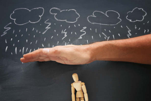Employee protecting employees - blackboard drawing of storm with lightning, hand protecting wooden doll