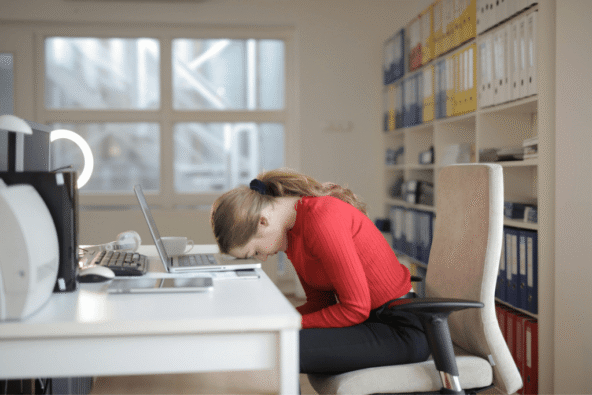Lady with head on office desk - burnout.